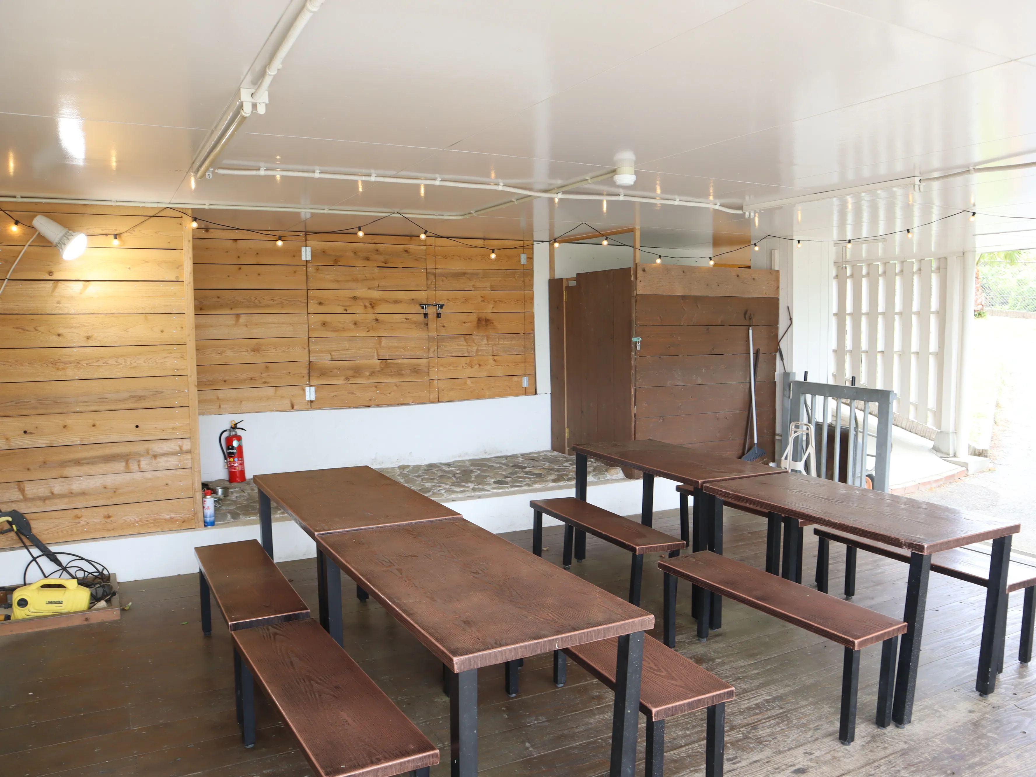 屋根の下にテーブルとベンチを並べたBBQエリア